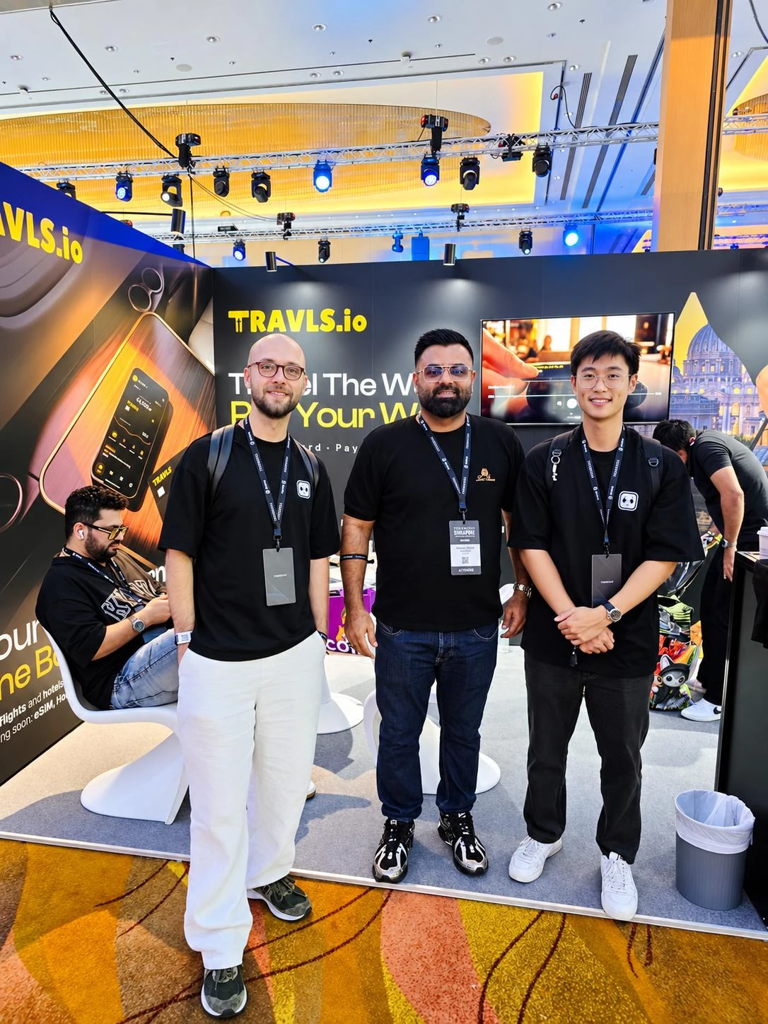 Three guests pictured in front of the Travls booth at TOKEN2049 Singapore